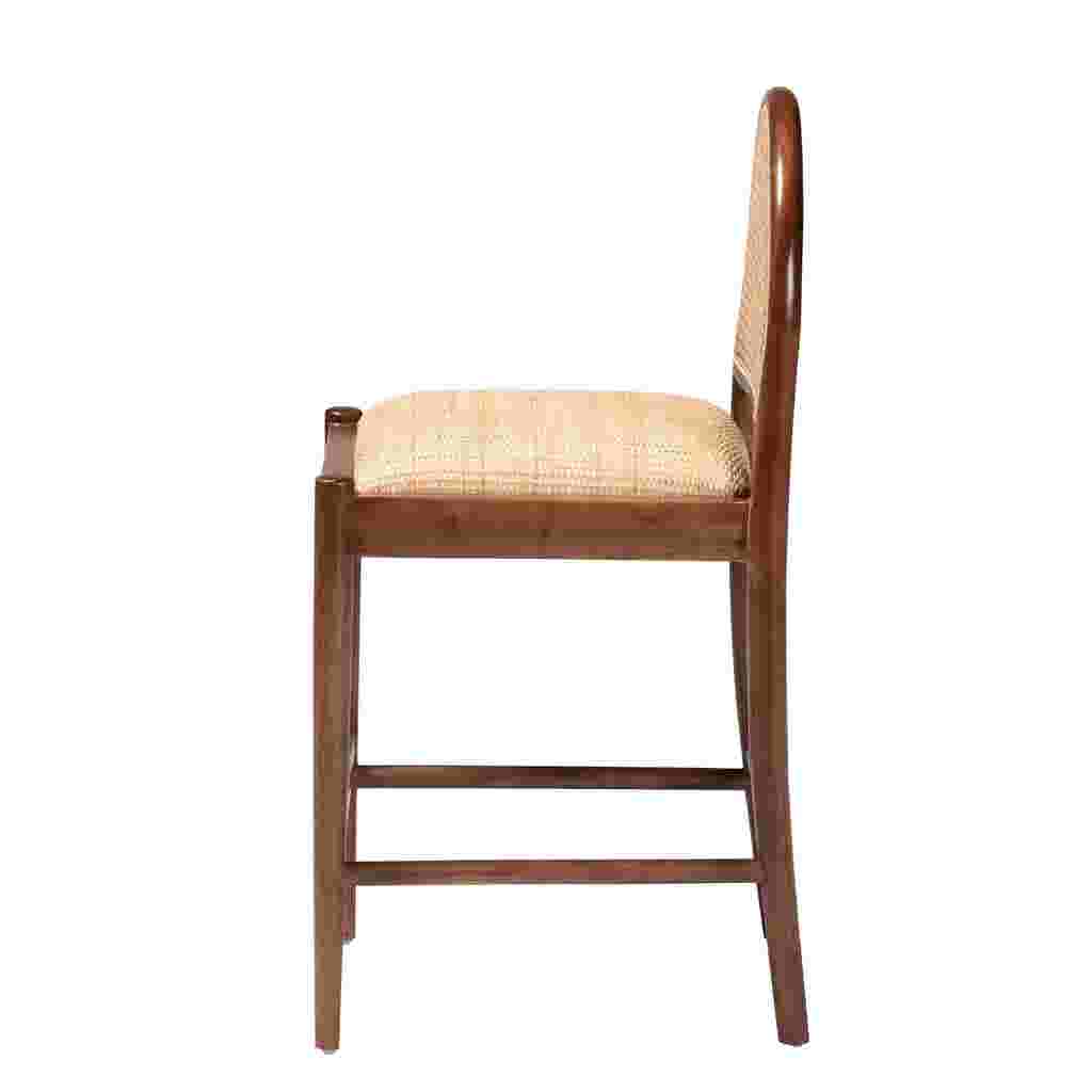 A side view of a wooden counter stool with a woven cane back and seat.