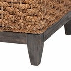 Corner detail of square seagrass storage ottoman with dark tapered legs