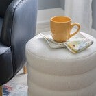 White sherpa round ottoman used as bedside table with mug