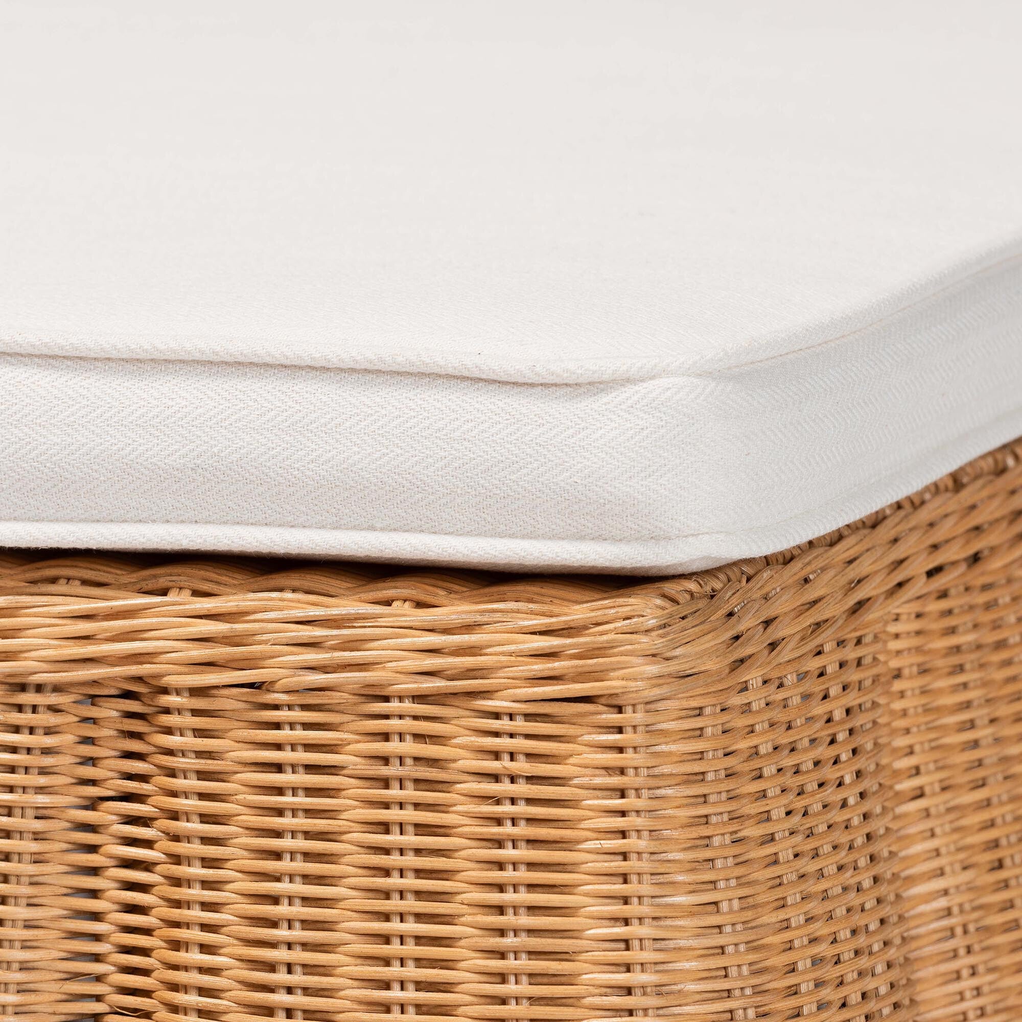 Close-up of white cushion edge and woven rattan ottoman side